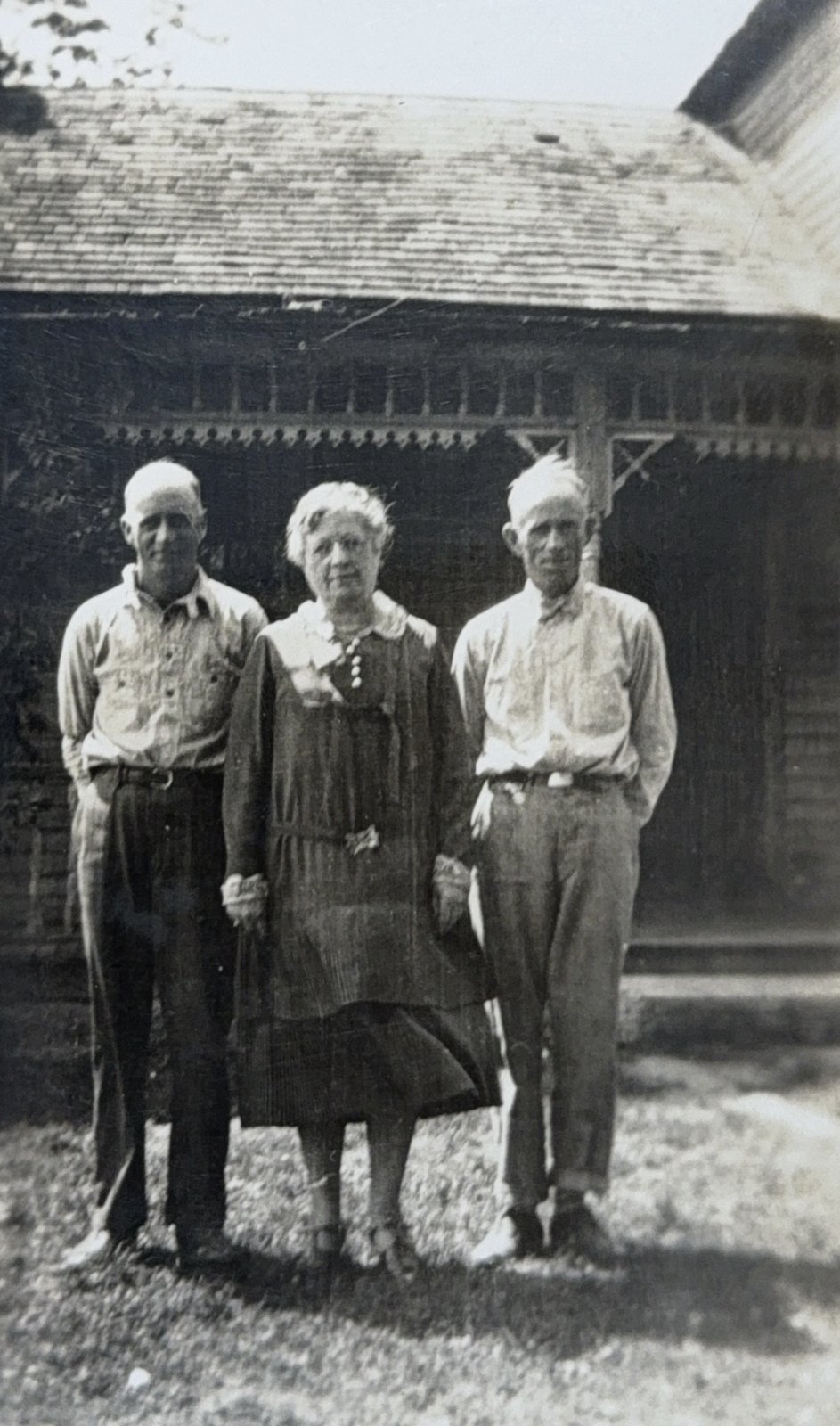 Three family members standing before a farmhouse porch