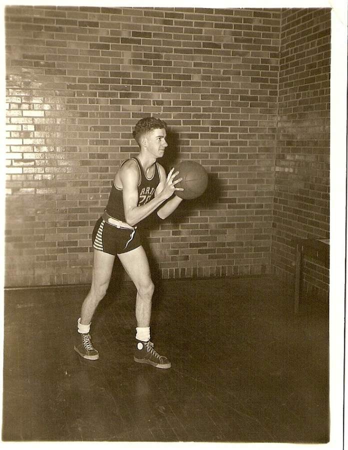 Young man in a basketball uniform holding a ball